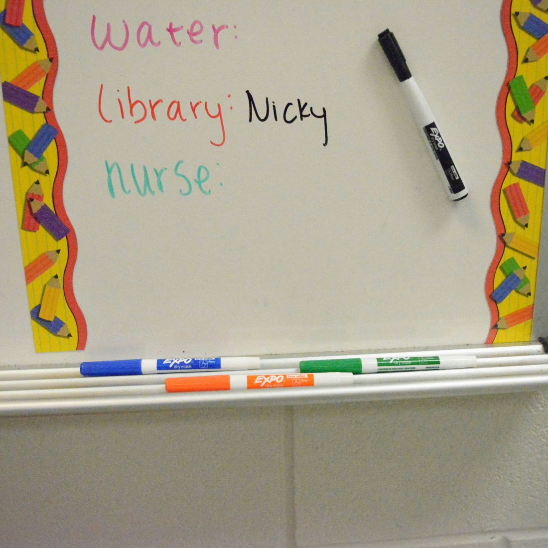 who-is-out-of-classroom-board-with-colorful-expo-markers-beneath.jpg